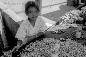 Menina vendendo pimentas em uma barraca de mercado